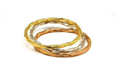 Lot 1900 - A SET OF THREE 18CT THREE COLOUR GOLD OVAL HINGED BANGLES (3)